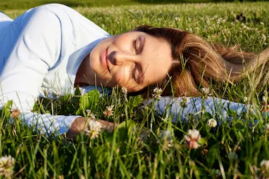 Woman lying in a grassy field feeling relaxed after allergy treatment with Advanced Allergy Therapeutics (AAT) in New Jersey